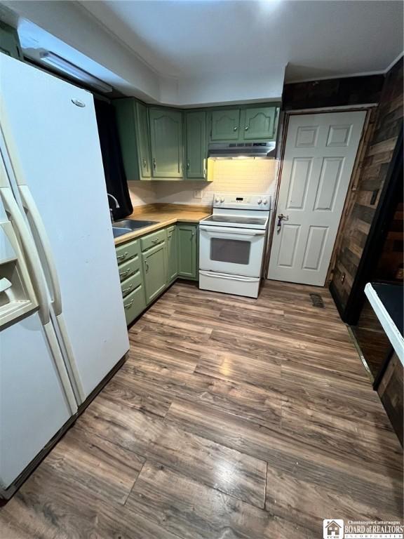 kitchen with sink, dark hardwood / wood-style floors, green cabinets, white appliances, and backsplash