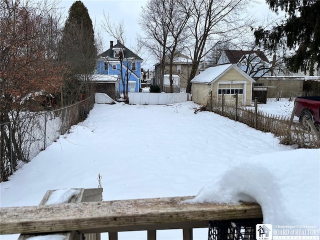 snowy yard with a garage and an outdoor structure