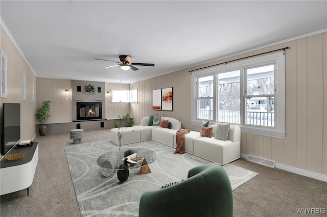 carpeted living room featuring ornamental molding and ceiling fan