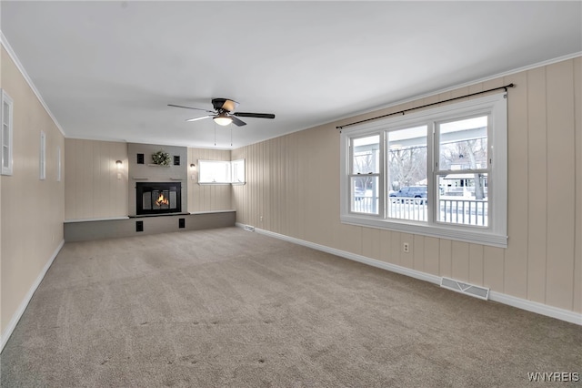 unfurnished living room featuring ceiling fan, ornamental molding, and light carpet