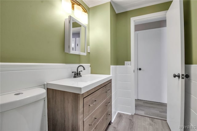 bathroom with vanity, wood-type flooring, ornamental molding, and toilet