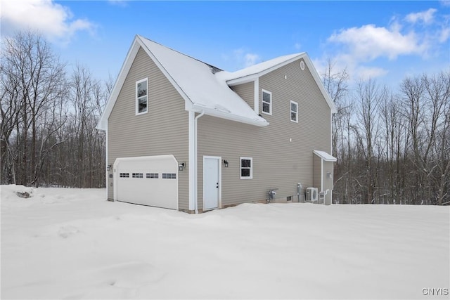 view of snowy exterior featuring a garage and central air condition unit