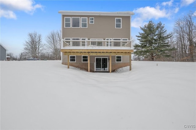 snow covered rear of property with a deck