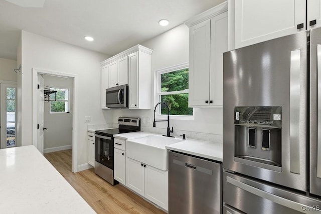 kitchen with white cabinetry, appliances with stainless steel finishes, sink, and light wood-type flooring