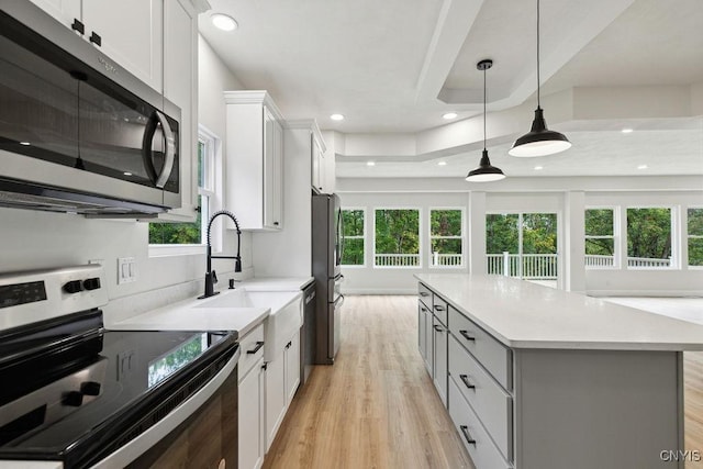 kitchen with a kitchen island, white cabinetry, appliances with stainless steel finishes, and pendant lighting