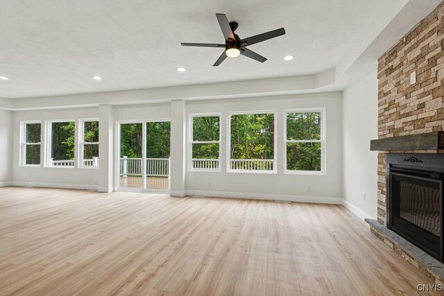 unfurnished living room featuring a fireplace, ceiling fan, and light wood-type flooring