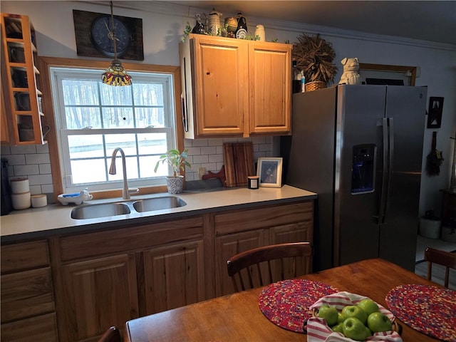 kitchen featuring stainless steel refrigerator with ice dispenser, sink, crown molding, pendant lighting, and decorative backsplash