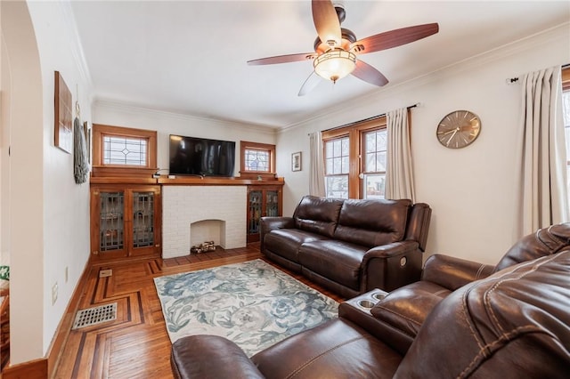 living room featuring parquet flooring, ceiling fan, ornamental molding, and a fireplace