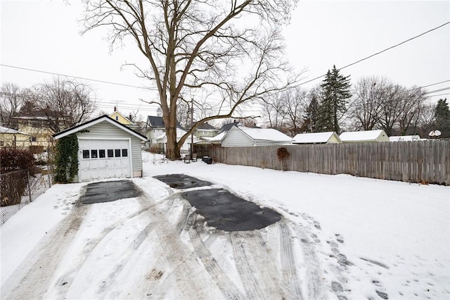 snowy yard featuring an outbuilding and a garage