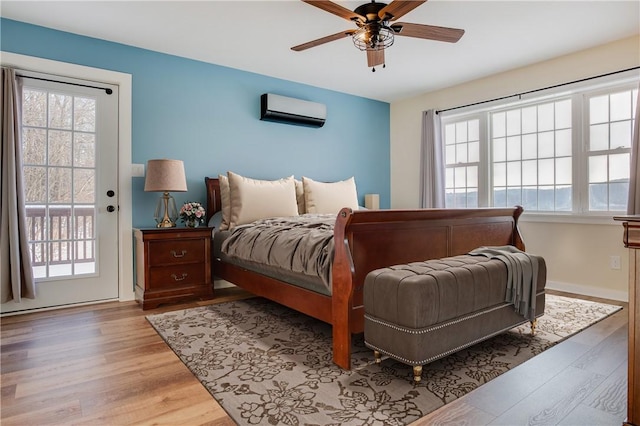 bedroom with multiple windows, light hardwood / wood-style floors, and a wall mounted AC