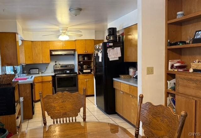 kitchen featuring electric stove, sink, ceiling fan, black refrigerator, and light tile patterned flooring