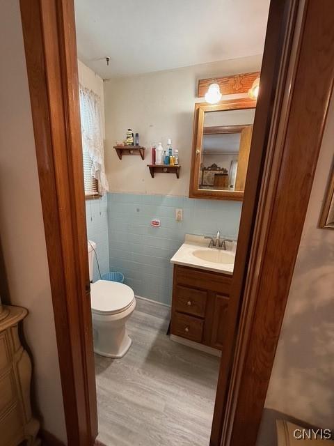 bathroom featuring hardwood / wood-style flooring, vanity, toilet, and tile walls