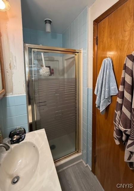 bathroom with walk in shower, sink, tile walls, and hardwood / wood-style flooring