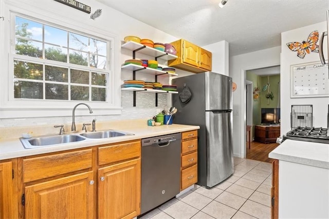 kitchen with sink, light tile patterned floors, stainless steel fridge, backsplash, and black dishwasher