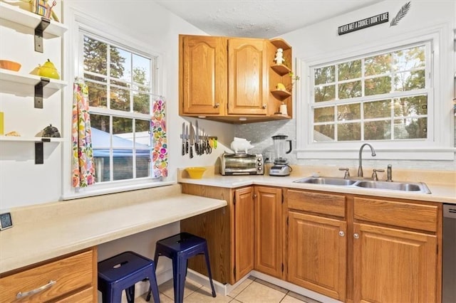 kitchen featuring stainless steel dishwasher, sink, a textured ceiling, and light tile patterned floors