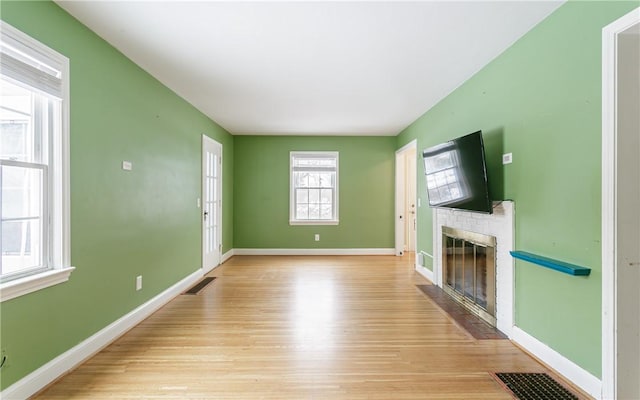 unfurnished living room with a brick fireplace and light hardwood / wood-style flooring