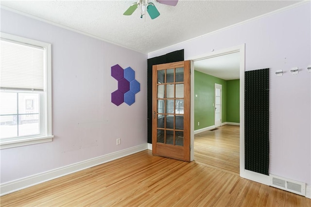 empty room with ceiling fan, wood-type flooring, and a textured ceiling