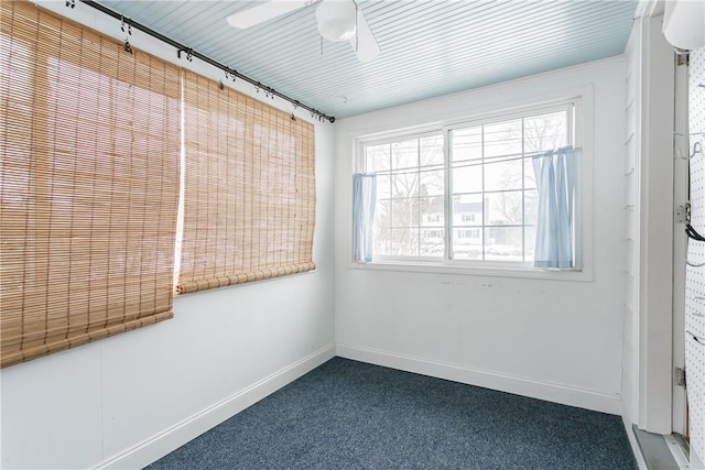 empty room with ceiling fan, track lighting, and dark carpet