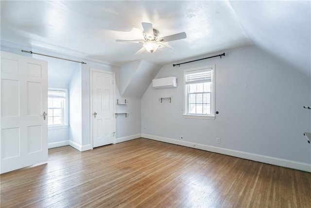 bonus room featuring an AC wall unit, wood-type flooring, vaulted ceiling, and a wealth of natural light