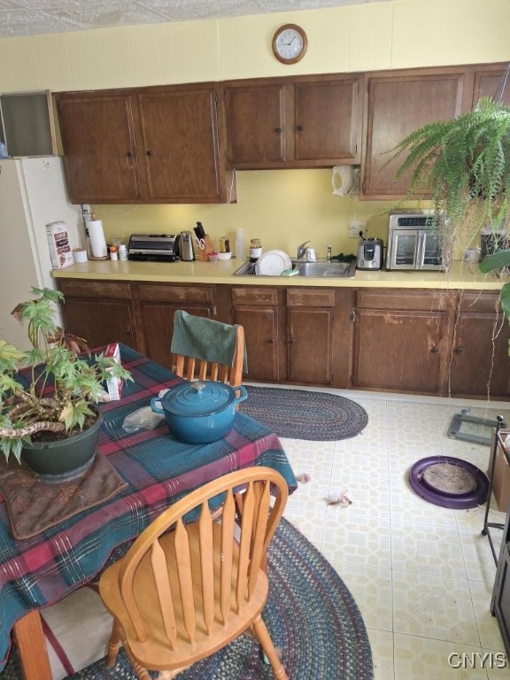 kitchen featuring light tile patterned flooring, white fridge, sink, and dark brown cabinets