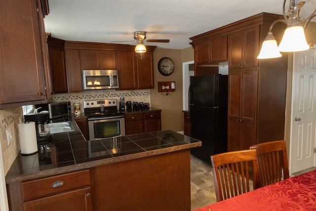 kitchen with ceiling fan, backsplash, stainless steel appliances, decorative light fixtures, and kitchen peninsula