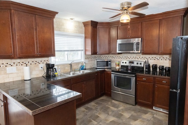 kitchen with sink, ceiling fan, stainless steel appliances, tasteful backsplash, and kitchen peninsula