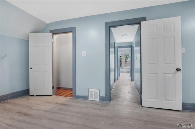 hall featuring vaulted ceiling and light hardwood / wood-style floors