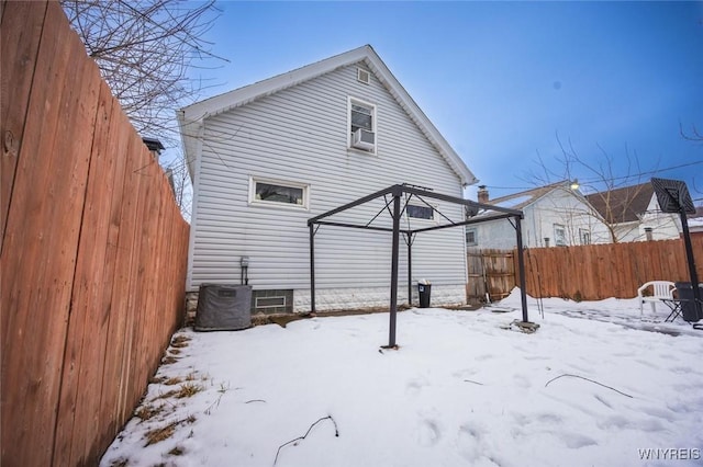 snow covered back of property featuring central AC unit