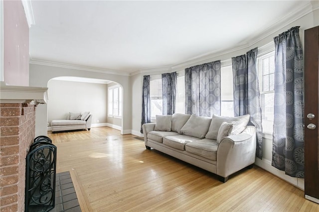 living room with ornamental molding, light hardwood / wood-style floors, a brick fireplace, and a wealth of natural light