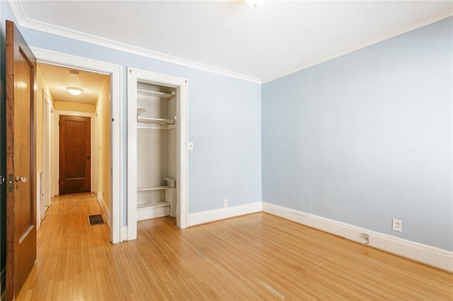 unfurnished bedroom with crown molding, a closet, and light hardwood / wood-style flooring