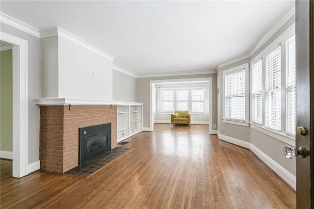 unfurnished living room with ornamental molding, a brick fireplace, and hardwood / wood-style floors