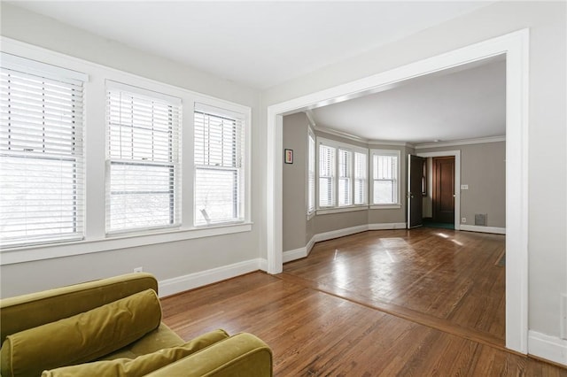 unfurnished living room with hardwood / wood-style flooring and crown molding