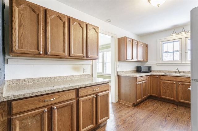 kitchen featuring wood-type flooring, sink, and light stone counters