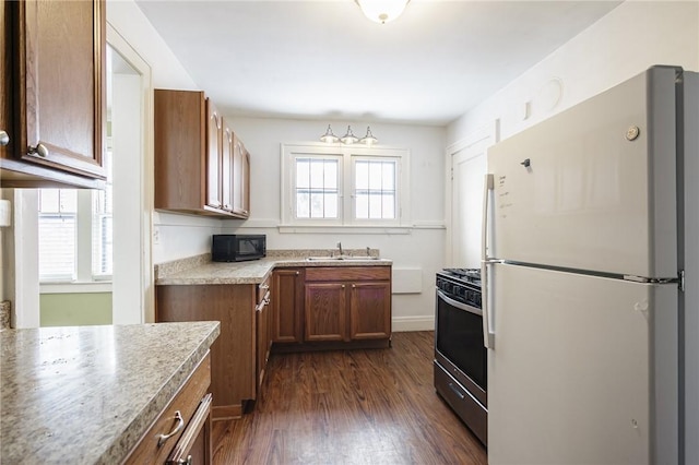 kitchen with gas range, white fridge, sink, and dark wood-type flooring