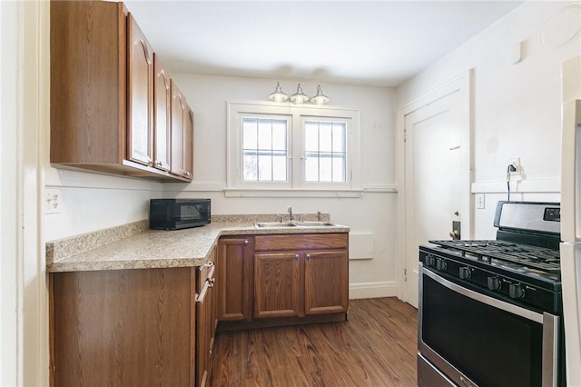 kitchen featuring dark hardwood / wood-style flooring, sink, and stainless steel gas range oven