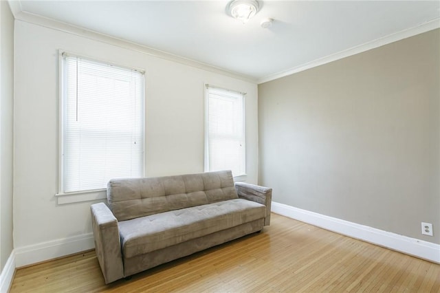 living area with ornamental molding, plenty of natural light, and light wood-type flooring