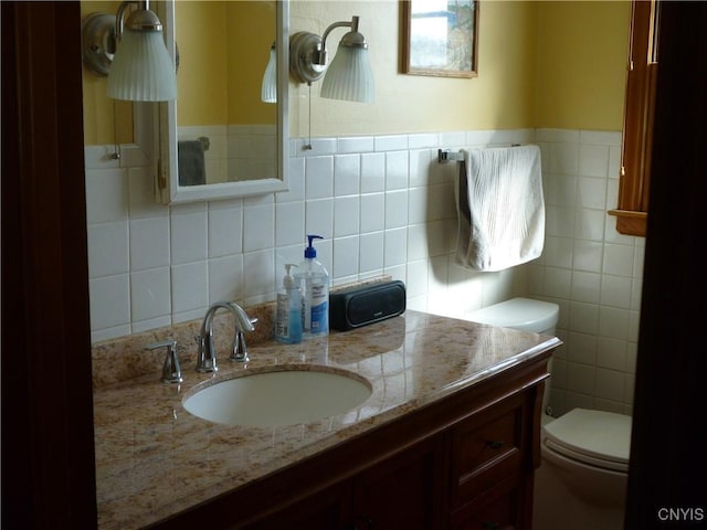 bathroom with vanity, tile walls, and toilet