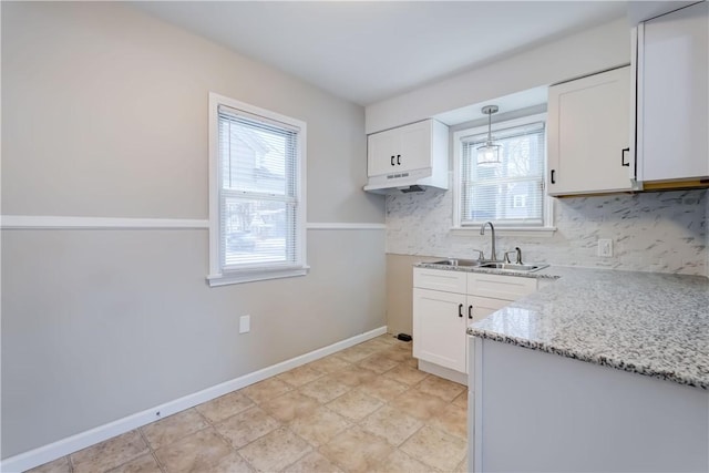 kitchen with white cabinetry, light stone counters, and decorative light fixtures