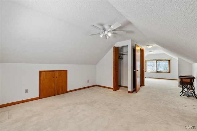 additional living space featuring ceiling fan, lofted ceiling, light colored carpet, and a textured ceiling