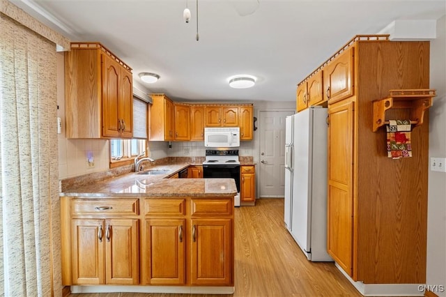 kitchen featuring sink, white appliances, light hardwood / wood-style floors, light stone countertops, and kitchen peninsula