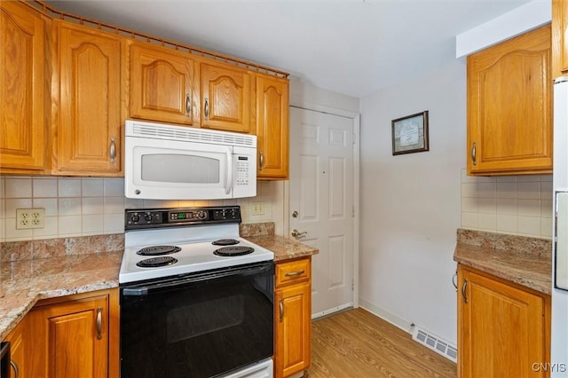 kitchen featuring light stone counters, light wood-type flooring, decorative backsplash, and range with electric stovetop