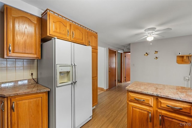 kitchen featuring light hardwood / wood-style flooring, ceiling fan, tasteful backsplash, light stone countertops, and white fridge with ice dispenser