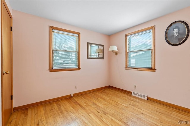 empty room with plenty of natural light and light hardwood / wood-style floors