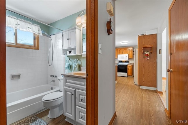 full bathroom with vanity, hardwood / wood-style floors, tiled shower / bath combo, and toilet