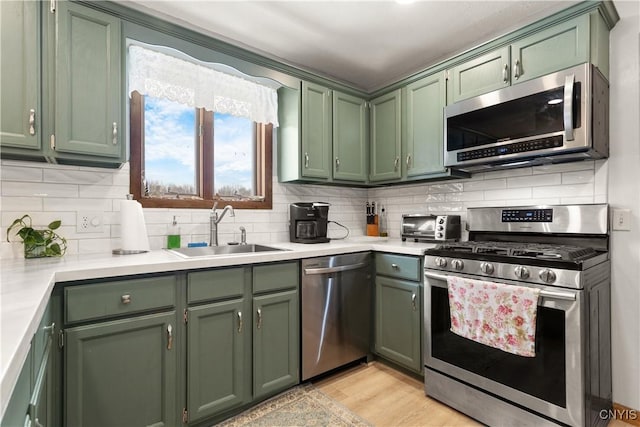 kitchen featuring sink, green cabinets, light hardwood / wood-style floors, and appliances with stainless steel finishes