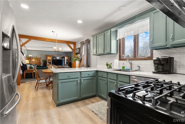 kitchen with green cabinetry, stainless steel fridge, decorative light fixtures, and kitchen peninsula