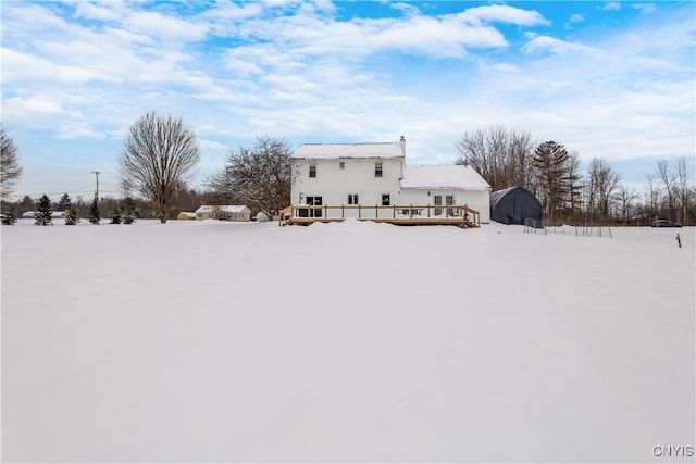 snow covered back of property with a deck