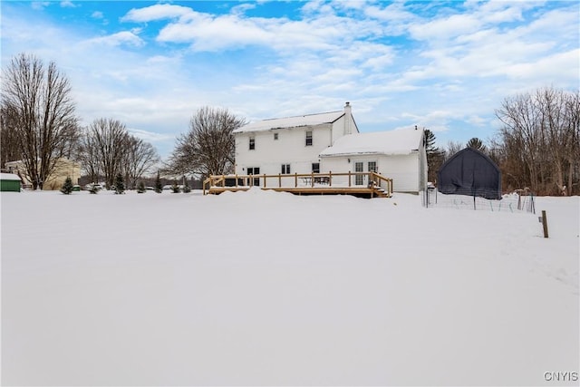 snow covered rear of property featuring a wooden deck and a trampoline