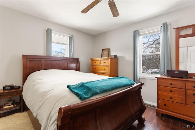 bedroom featuring dark wood-type flooring, ceiling fan, and multiple windows