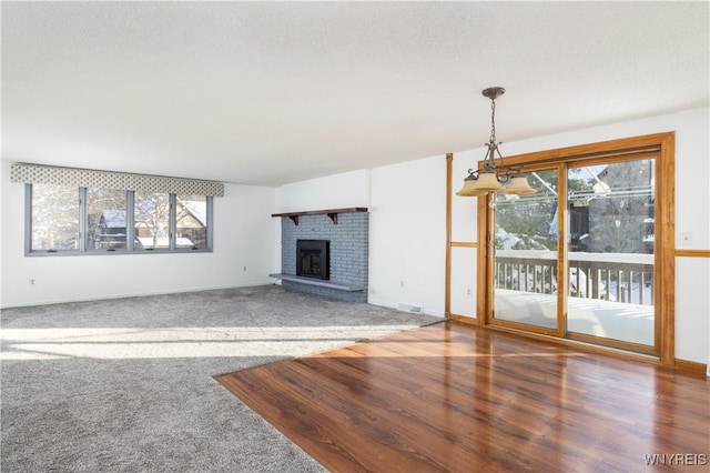 unfurnished living room featuring a brick fireplace, wood-type flooring, and a textured ceiling